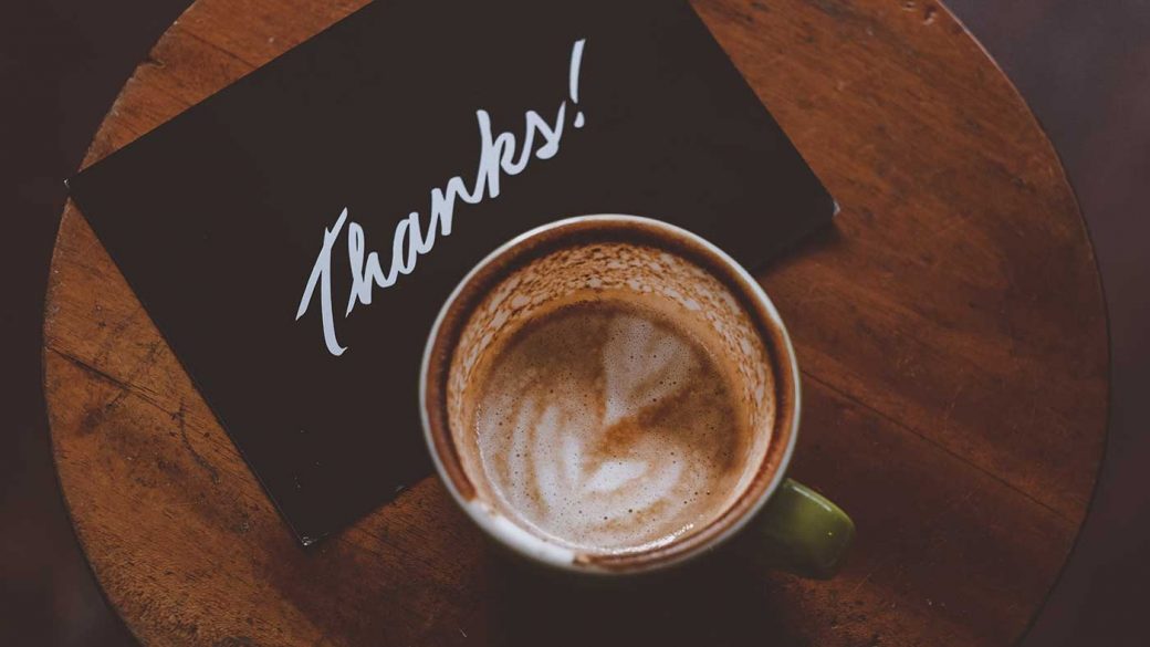 Thank you note on table next to cup of coffee