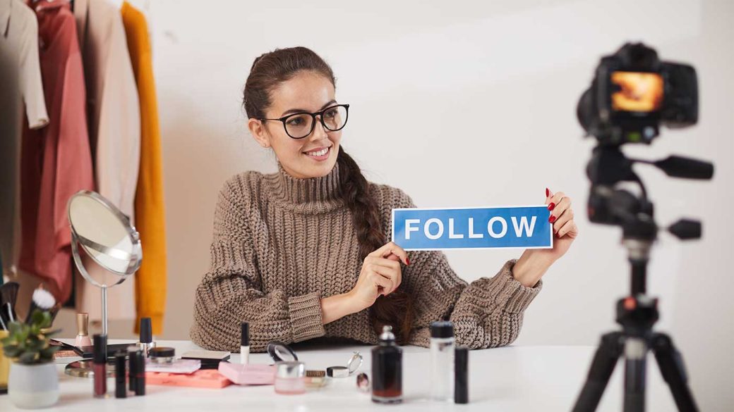 A TikTok influencer holding a ‘follow’ sign