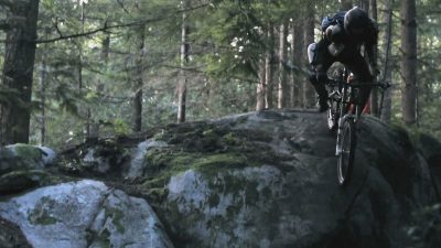 A one-armed mountain biker navigating through the woods.
