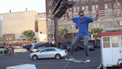 A man in a blue shirt riding a skateboard.