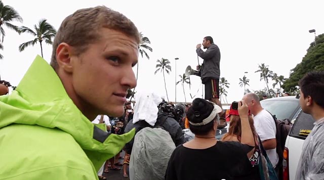 Pro surfer and MMA fighter Dustin Barca leads an anti-GMO rally as Surfing For Change founder Kyle Thiermann looks on. Screen shot from 'Pro Surfers vs GMOs'.