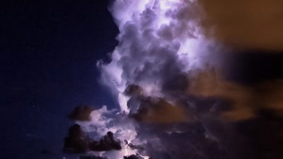 Lightning strikes amidst dark storm clouds over the ocean.