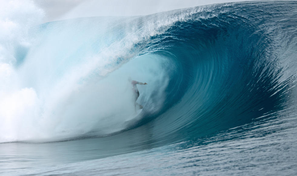 A surfer competing in the Billabong Pro Tahiti 2014, riding a wave in the ocean.