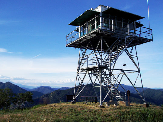 A metal fire tower on top of a hill available for rent.