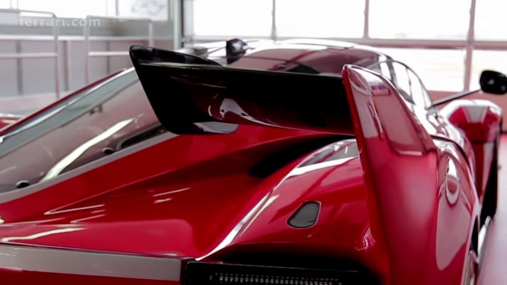 A red sports car, the FXX K Hypercar, is parked in a garage.