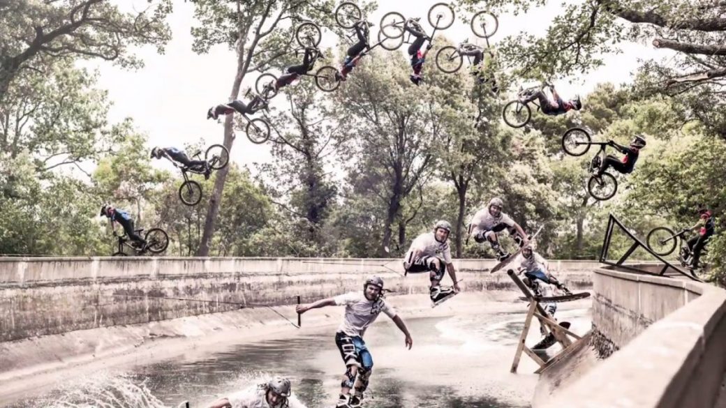 A group of bikers doing backflips in a river.