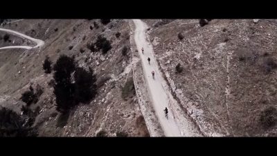 A group of people riding down an alpine dirt road on their road steeds.