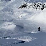 A person is skiing down a snow-covered slope near Valdez with Valdez Heli Ski Guides.