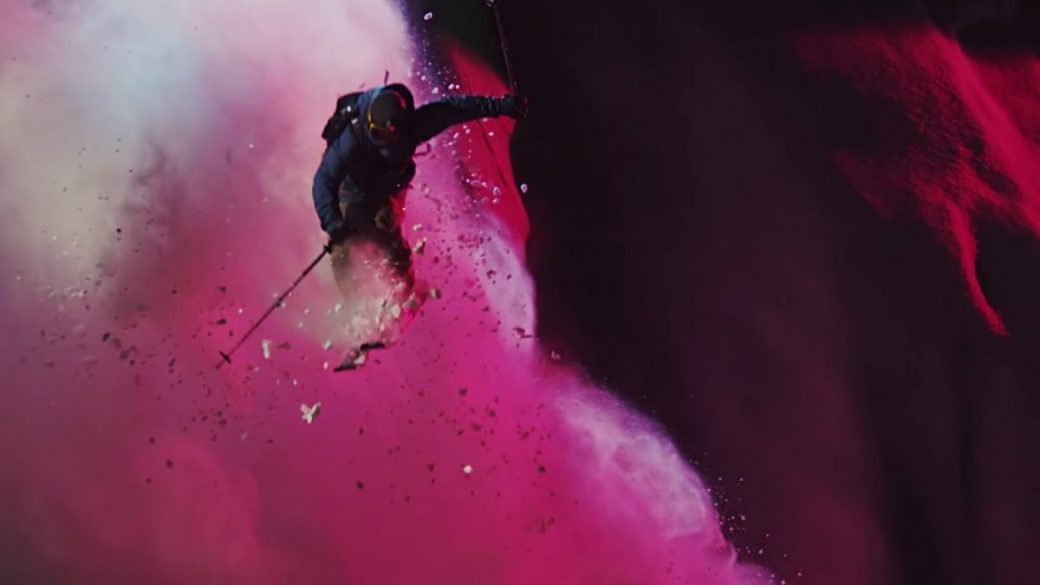 A skier soaring through a cloud of colorful smoke.