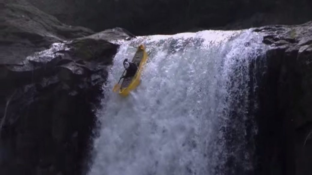 A man is paddling down a waterfall in a canoe.