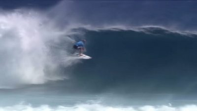A surfer rides a large wave on a surfboard during the Fiji Pro competition.