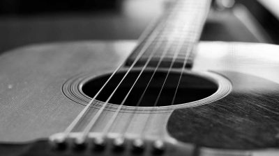 A black and white photo of an acoustic guitar perfect for music videos and social media posts.