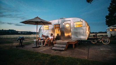 Man and woman sitting in front of caravan at dusk