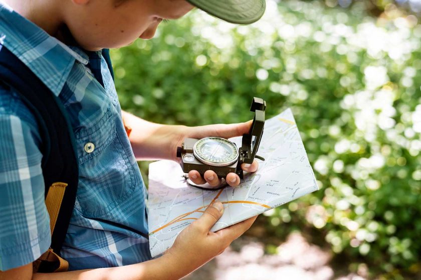 Boy using a map and compass to navigate