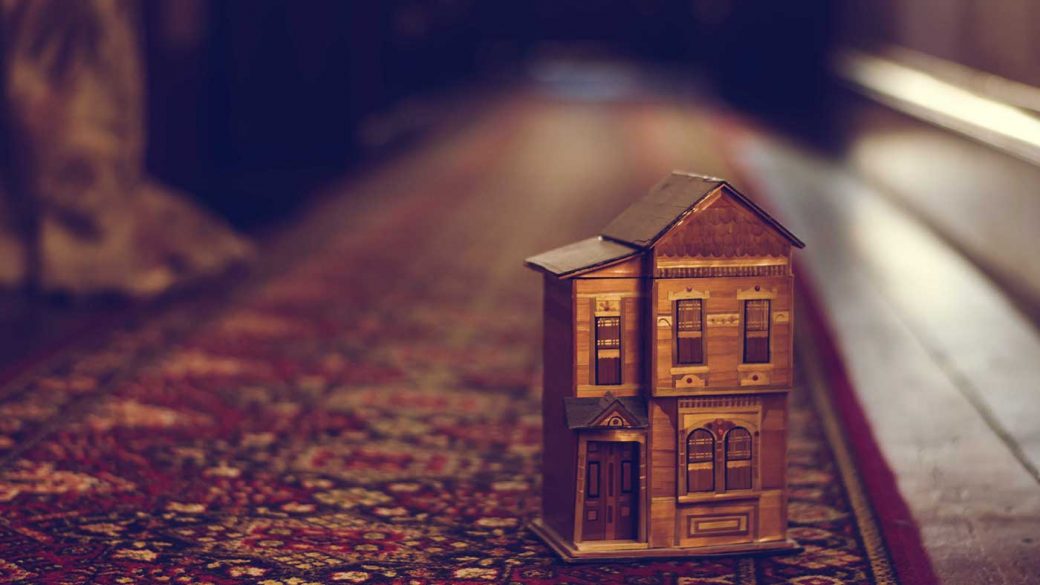 Wooden miniature house on red carpet