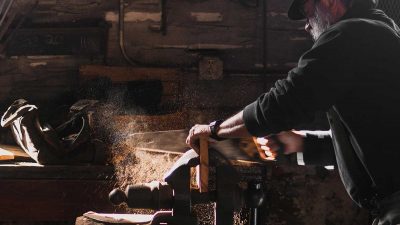 Man cutting plank of wood with a hand saw