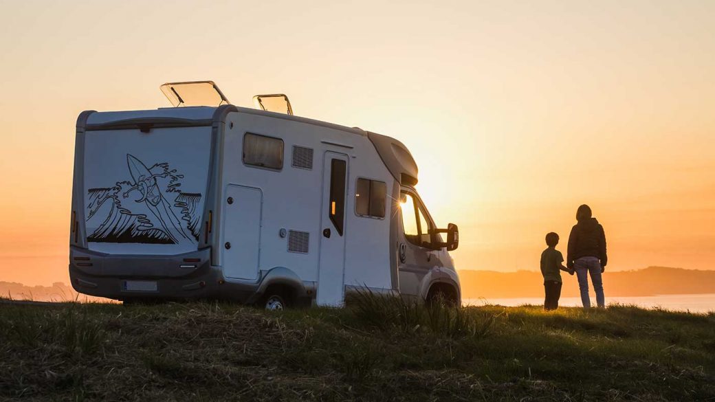 Two campers standing next to RV looking at sunset
