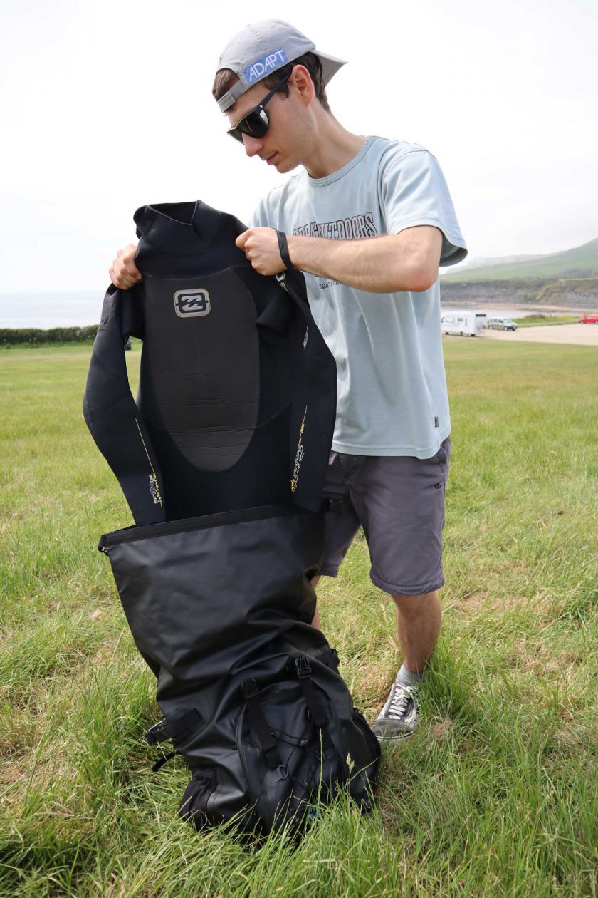 Pulling a wetsuit out of the DryTide 50L waterproof backpack