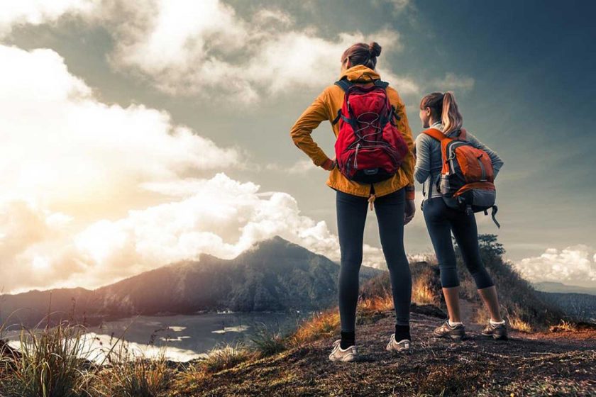 Two female hikers at the top of a mountain looking at a lake below