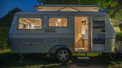 Caravan parked next to tree under a starry night sky