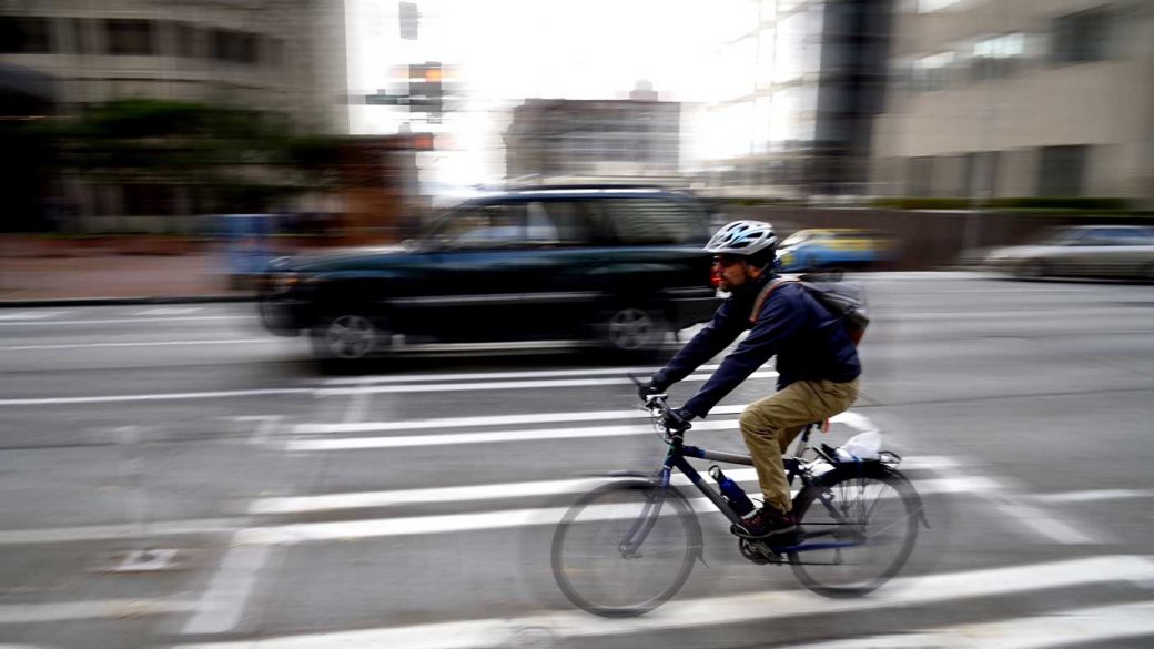 Bike commuter wearing helmet and riding on a busy city road