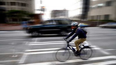 Bike commuter wearing helmet and riding on a busy city road