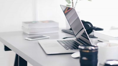Laptop, phone and camera lenses organised on a tidy office desk