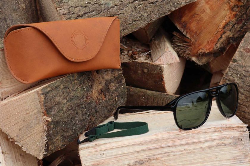The Vallon Howlin’ sunglasses on a wood pile with case and strap