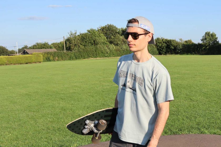 Holding a SwellTech Hybrid surfskate skateboard while wearing the Vallon Howlin’ sunglasses