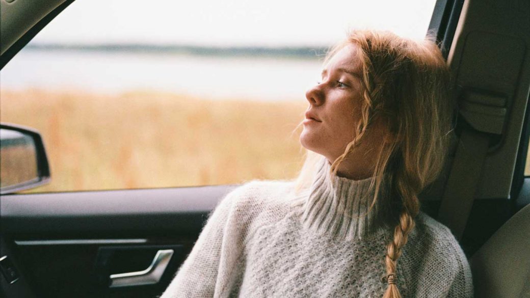 Woman wearing a sweater gazing out of a car window