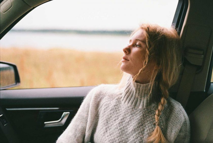 Woman wearing a sweater gazing out of a car window