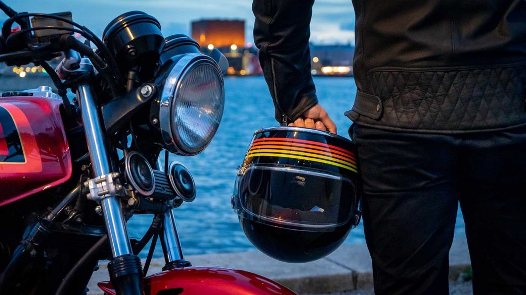 Motorcyclist holding a vintage full-face motorcycle helmet