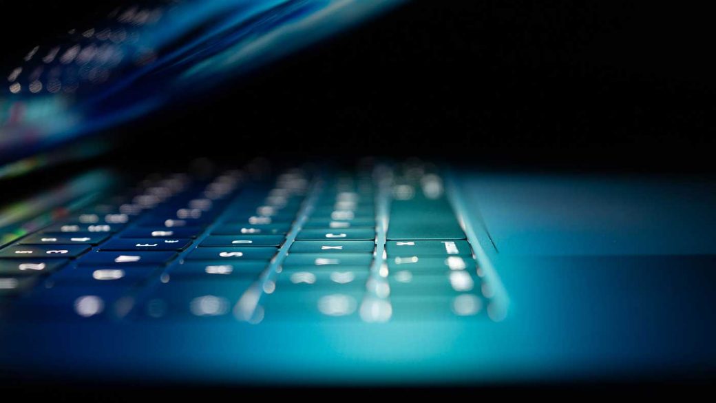 Close-up of laptop keyboard under blue light