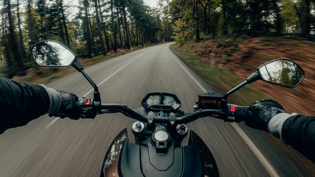 Helmet cam view of a black motorcycle on a forest road