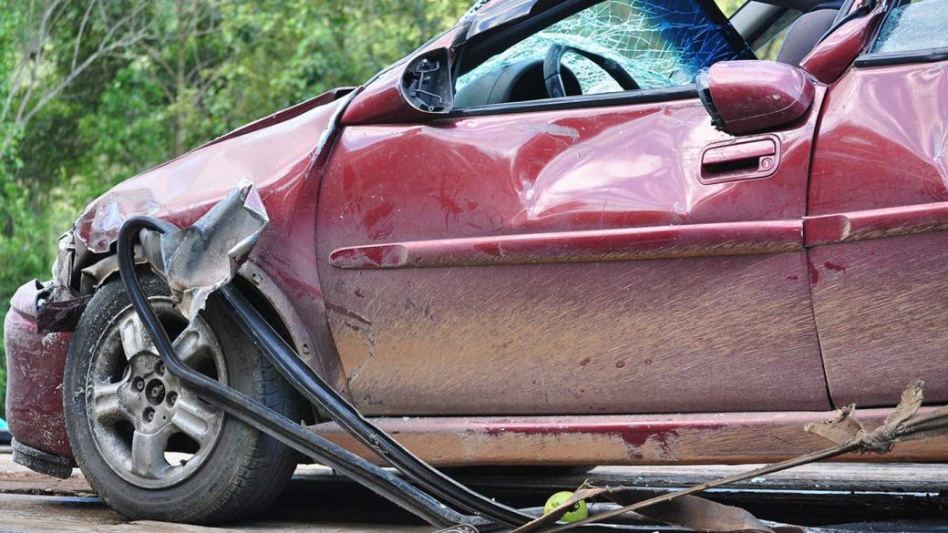 Damaged red car on a tow truck after a car accident