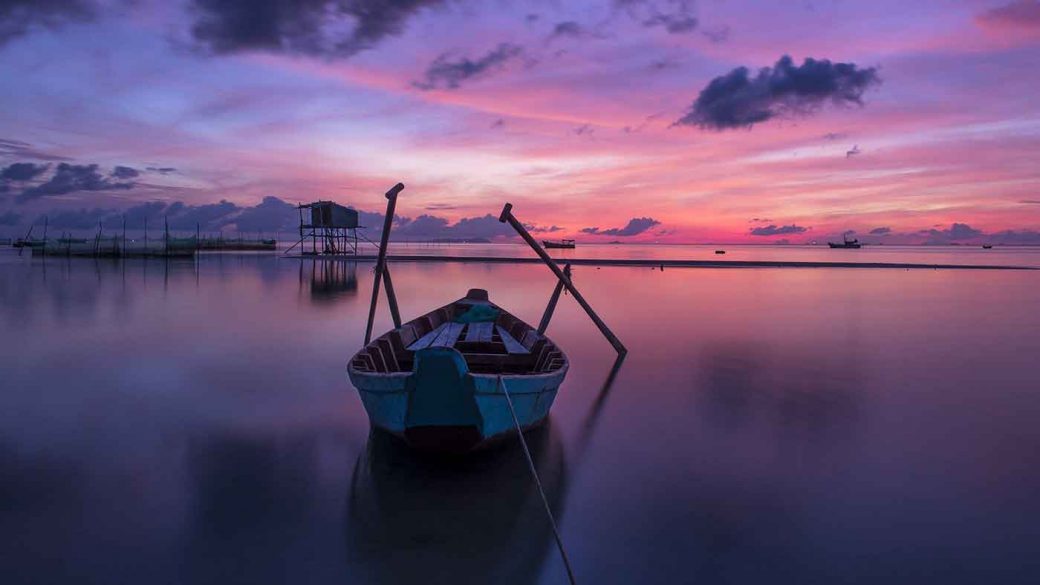 A small boat in unknown shallow waters at sunset
