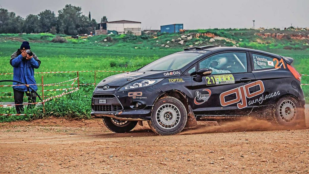 A motorsports photographer taking a photo of a rally car