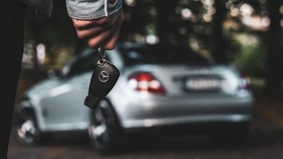 Man holding the keys to his new silver Mercedes-Benz car