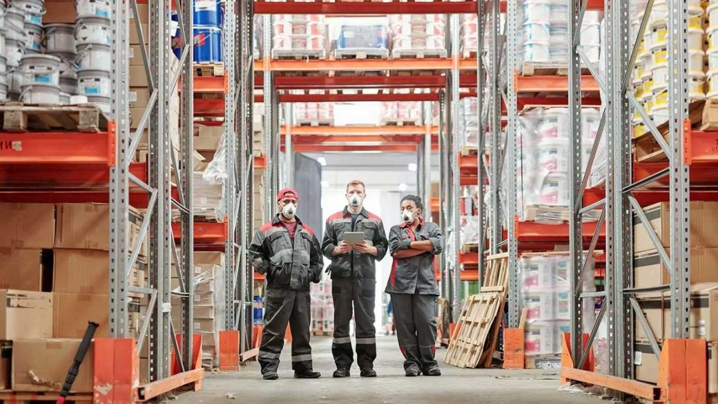 Three warehouse workers wearing safety clothing
