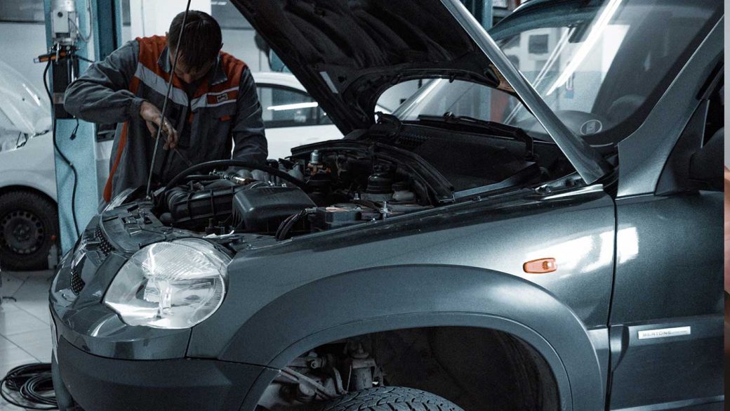 Car mechanic fixing a grey SUV