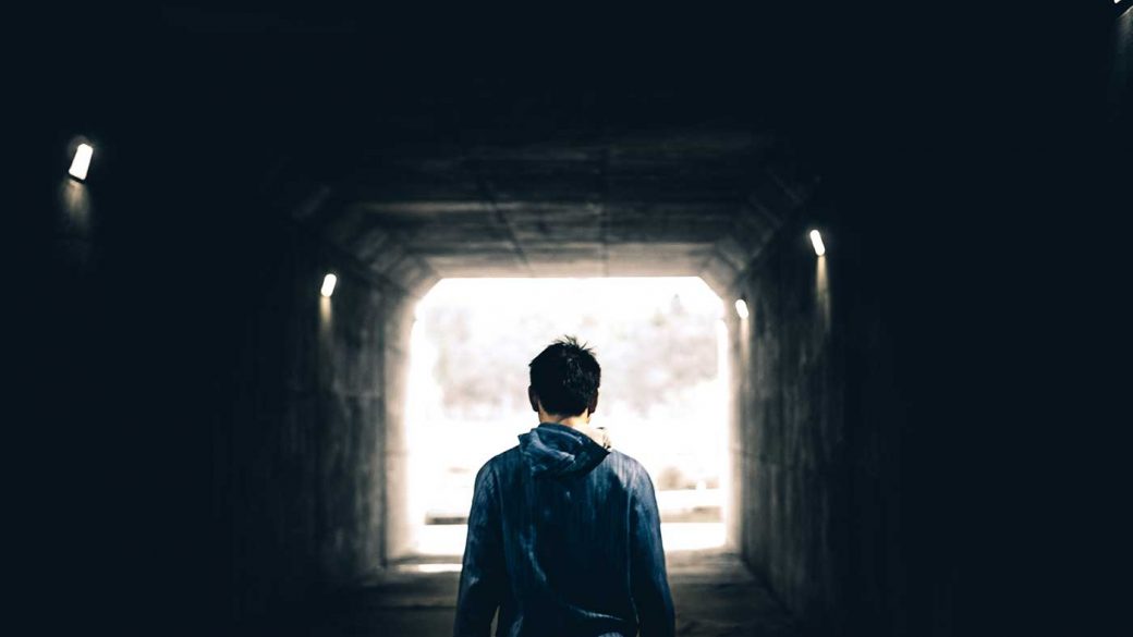 Man walking towards the light at the end of a tunnel