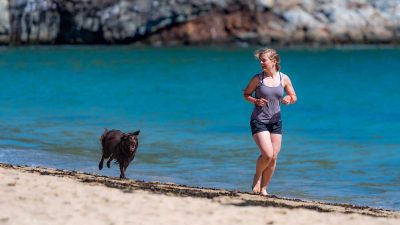 Woman running on the beach with her dog