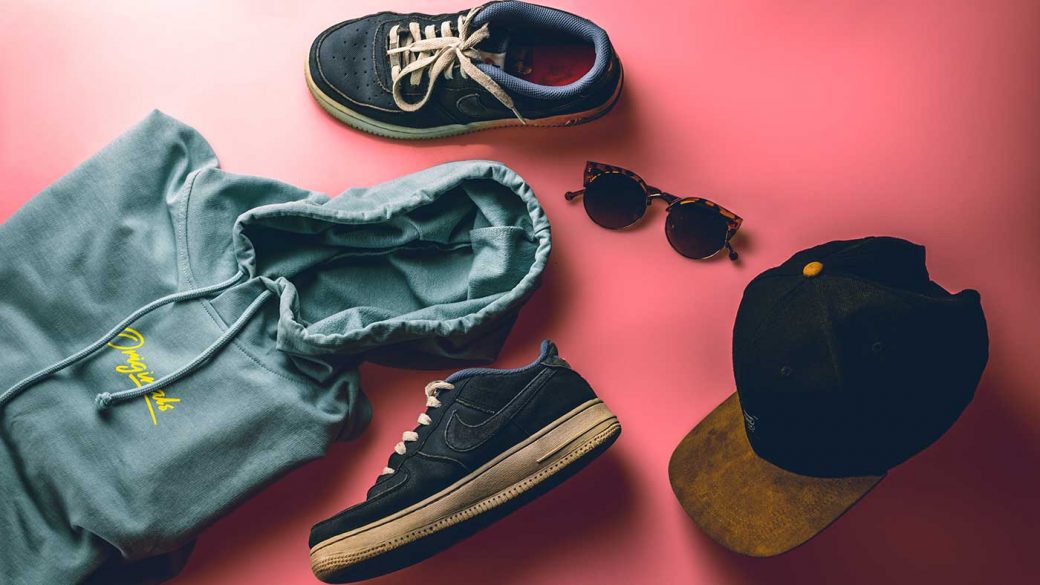 Hoody, shoes, sunglasses and baseball hat against a red background