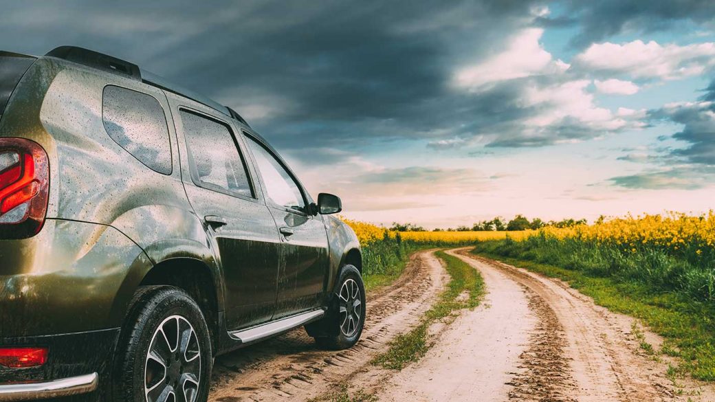 Green SUV parked on a dirt road