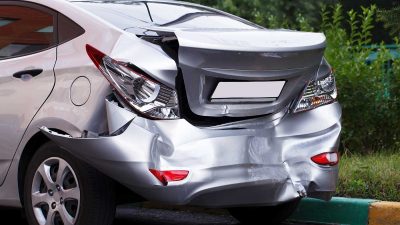 Silver car that has a big dent in the trunk after an rear-end car accident