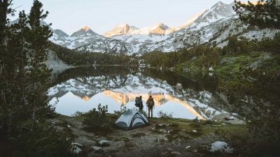 Two hikers camping next to a lake