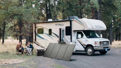 Two people sat by their motorhome while their power station charges from a solar panal