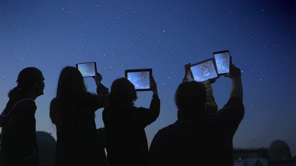 Group of students using tablets to study the night sky