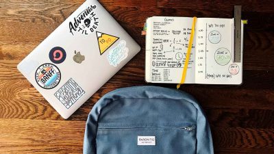 Laptop, notebook and backpack on wooden desk