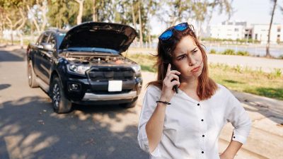 Stressed woman calling her car insurance company following a road accident